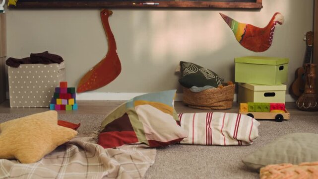 Tilt up no people shot of kindergarten classroom interior with alphabet flashcards scattered on floor with cozy cushions and educational chalkboard with rules, weather chart and daily schedule