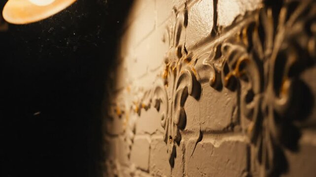 Low angle shot of a vintage brick wall with decorative plasterwork illuminated by a warm light
