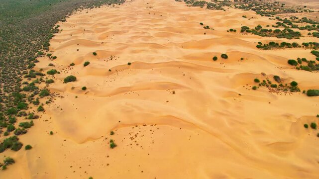 Tracking drone shot of golden sand dunes in Jaisalmer, Rajasthan. Captures the vast desert terrain and natural patterns of the Thar Desert from a smooth aerial perspective.
