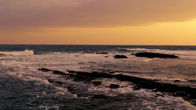 Mare con onde e scogliera bassa al tramonto