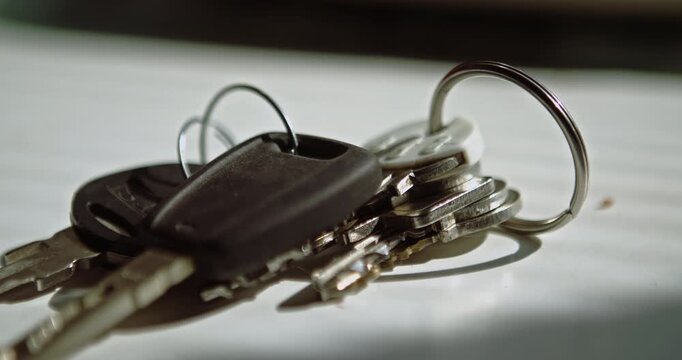 A hand sets a bunch of car and house keys down onto a kitchen worktop. Ideal for arriving home and end-of-day routines.