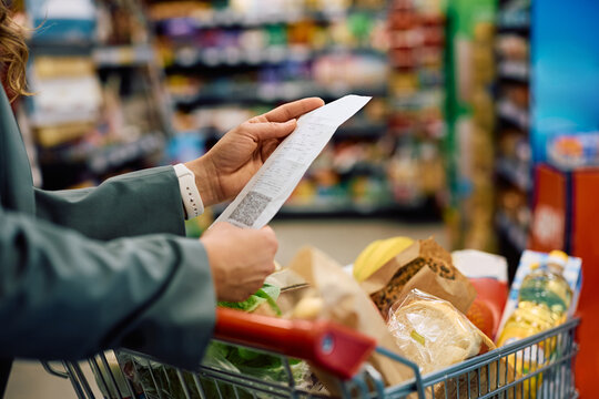 Close up of woman checking the bill after buying groceries in supermarket.