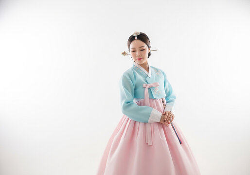 Young woman in traditional Korean hanbok holding a pastel blue clutch in studio portrait