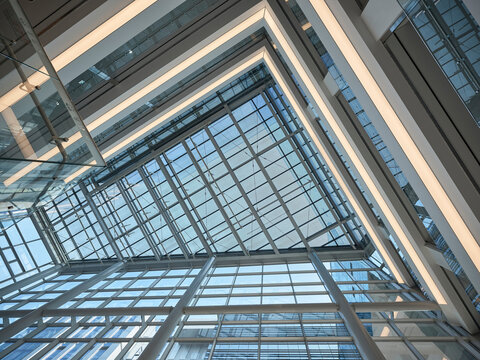Looking up through glass atrium grid and skybridge in modern architecture