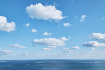 Obraz premium Open sea horizon beneath bright blue sky with scattered clouds