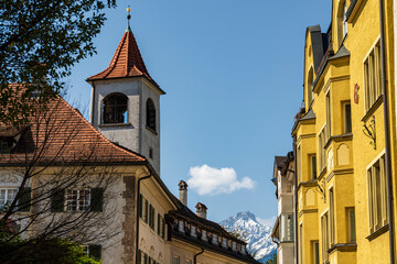 Obraz premium Bell tower and buildings with tiled roofs and mountain background