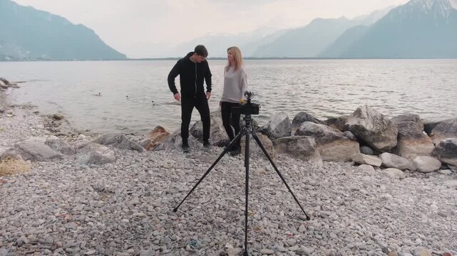 Caucasian couple posing in front of tripod with camera with Lake Geneva in Montreux, Switzerland, gimbal shot