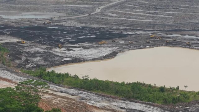 Aerial view of excavator and coal hauling truck activity, near a very deep excavation pit