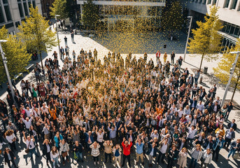 Obraz premium Large diverse crowd gathering in urban plaza with modern architecture and natural lighting