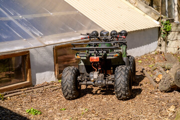 Utility quad bike on a farm next to a building equipped with a modern solar energy system. © Anna