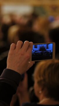 Auditorium at concert - people shooting performance on smartphone, music opera