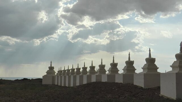 Buddhist ritual structures stupa in the Gobi desert, Mongolia. Architectural complex of Shambala. White stupas on the background of a picturesque cloudy sky on a summer day.