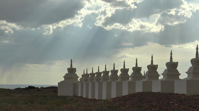 Buddhist ritual structures stupa in the Gobi desert, Mongolia. Architectural complex of Shambala. White stupas on the background of a picturesque cloudy sky on a summer day.