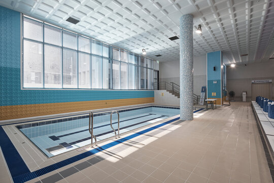 Pool deck with windows and blue tiled accents in bright natatorium