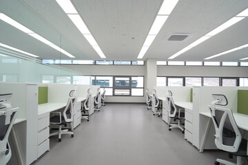 Fototapeta premium Long office aisle with white desks and bright window wall