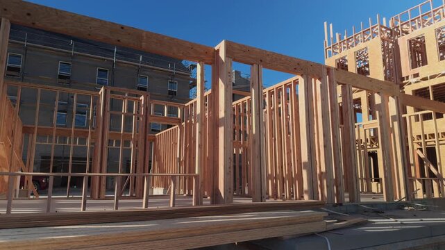 Wide slow pan of exposed wood framing beside unfinished apartment building.