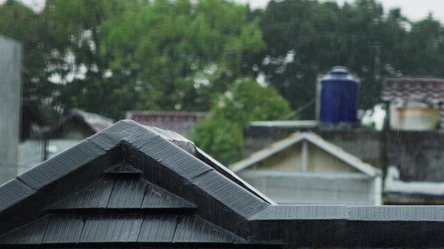 Tropical monsoon rain pours over clay roof tiles in Jakarta. Intermittent lightning flashes illuminate the stormy sky. High-intensity weather footage captured in Indonesia