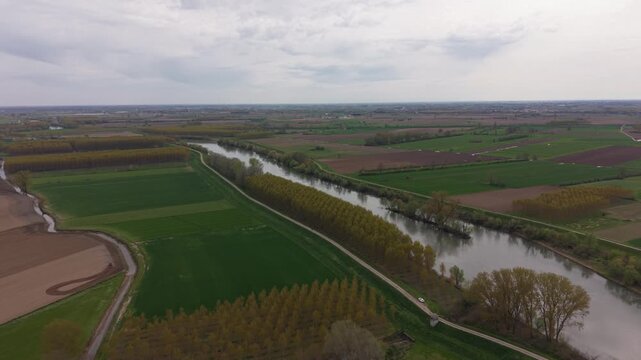 Aerial footage of River Oglio flowing through Parco Regionale dell'Oglio Sud, showcasing lush landscapes and natural surroundings in Lombardy, Italy.