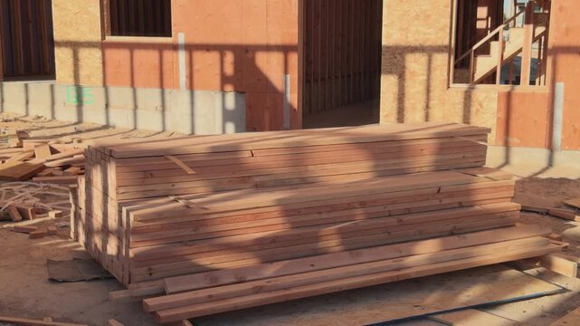 Slow upward pan from lumber stack to unfinished building entrance and framing.