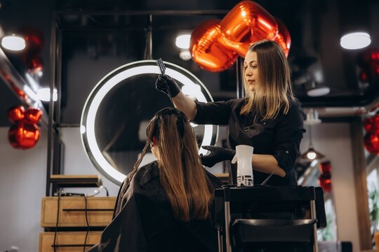 Hairdresser applying color to client's hair in salon