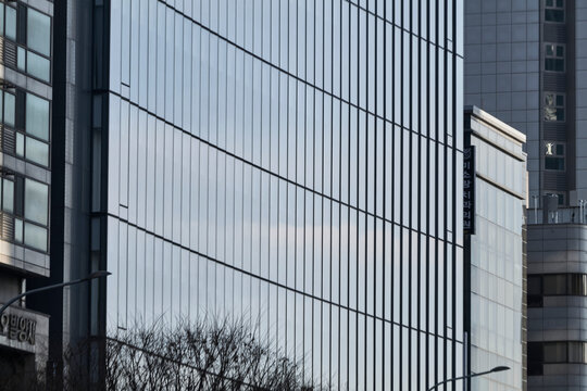 Curving glass office facade with vertical mullions in cityscape