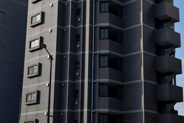 Dark apartment facade detail with stacked balconies and shadows © Namsun