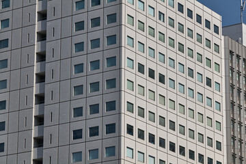 Pale apartment tower facade with square windows in dense city district © Namsun