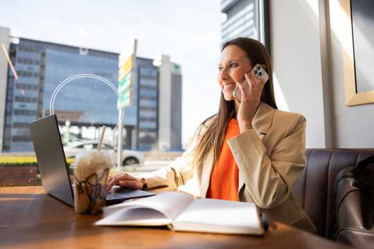 Businesswoman working with laptop and phone in a cafe during daylight