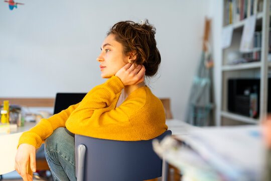 Young woman in a yellow sweater sitting at home thinking