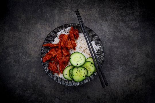 Vegan sweet chili beef strips with rice and cucumber salad in bowl