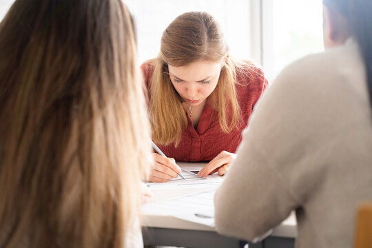 young woman with long hair, sitting at desk,