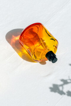 Luxury citrus perfume bottle casting colorful shadow in hard light