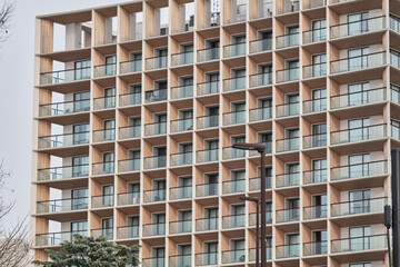 Long residential apartment facade with repeated balconies and warm color © Namsun
