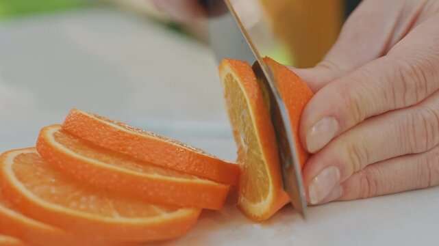 Stacked orange slices on cutting board arranged, chef hands slicing thin rounds into neat row, soft natural light, juicy segments and textured peel, precise knife technique, kitchen counter scene,