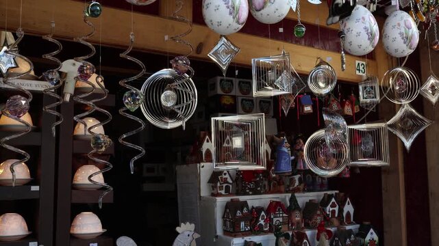 Colorful hanging wind spinners and metallic ornaments rotating in shop interior creating dynamic motion light reflections and visually engaging decorative retail display