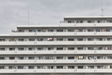 Long white apartment block facade and rooftop under gray sky © Namsun