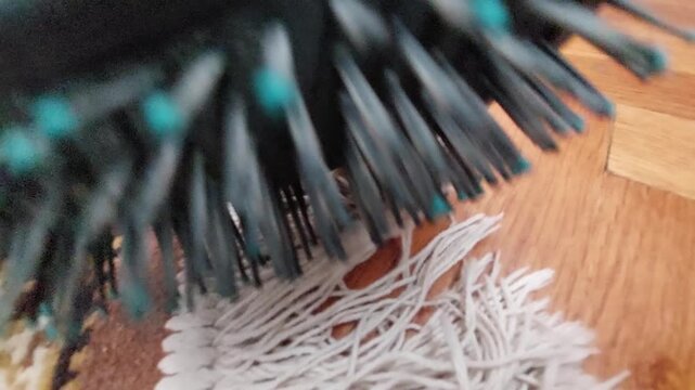 Brushing White Carpet Fringes with Hairbrush on Wooden Floor