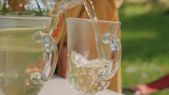 Sparkling drink poured into crystal glass, close up camp table shot with bubbles and condensation, bright outdoor backdrop and delicate glass reflections, refreshing picnic detail