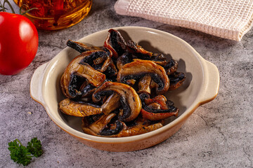 Fototapeta premium Grilled sliced mushrooms in a ceramic bowl with fresh tomato and parsley