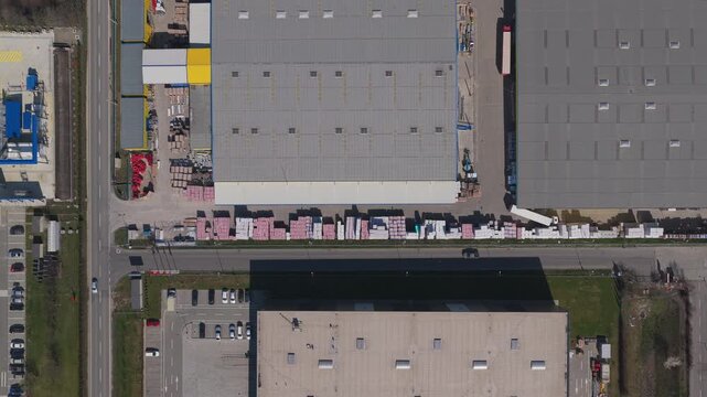 Detailed top down view of busy logistics center warehouses and stored materials in Brasov on a bright sunny day with a slow lateral aerial drone flight