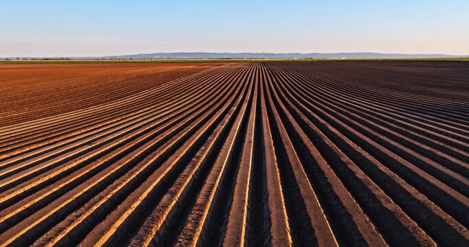 Aerial view flying over plowed farm field rows