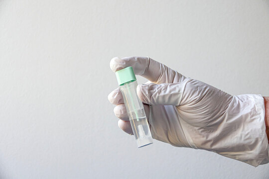 Person holds a test tube with clear liquid inside