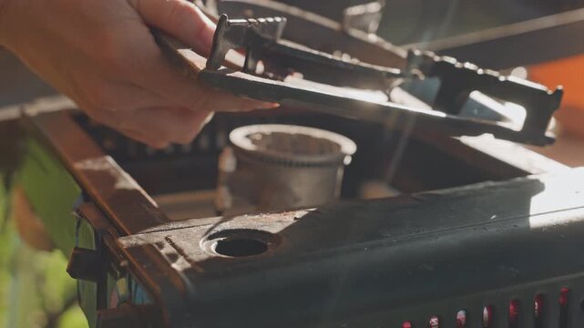 Hands assembling camping stove outdoors carefully. Quiet work fitting metal parts on camping stove in forest. Close examination of hands assembling stove components in sunlit natural setting