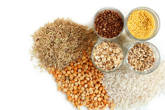 Various grains and cereals on white background: Rice, buckwheat, millet, and peas.