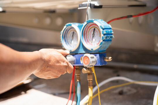 Technician checking air conditioning pressure with manifold gauge during maintenance repair and installation service, Hvac worker hand adjusting pressure gauge on air conditioner system