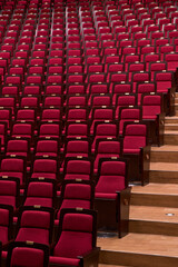 Fototapeta premium Pattern of red theater chairs and aisle steps in close up