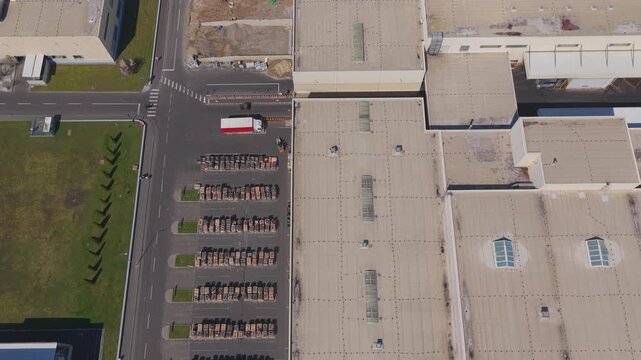 Detailed top down view of active factory yards with stored manufactured components and working forklifts in Brasov industrial zone on a bright spring day, slow backward drone flight