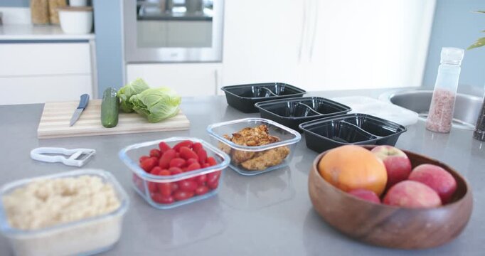 Camera moving forward, focusing on clear containers wooden fruit bowl and empty trays for packing