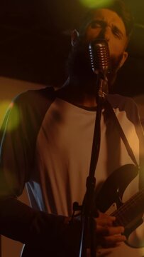 Vertical video: Cam moving in, lead singer playing guitar at mic, singing, band backing emotionally
