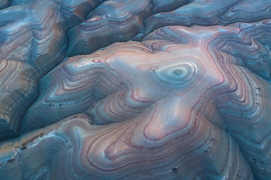 Aerial view of the mesmerizing, layered earth reveals a tapestry of swirling blues, reds, and browns, creating an otherworldly landscape of textured beauty, Hanksville, Utah, United States.